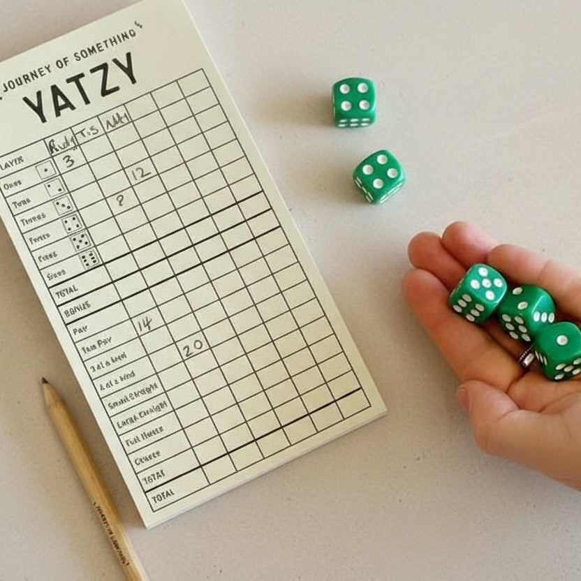 Yatzy game board with dice and a hand holding more dice on a white background