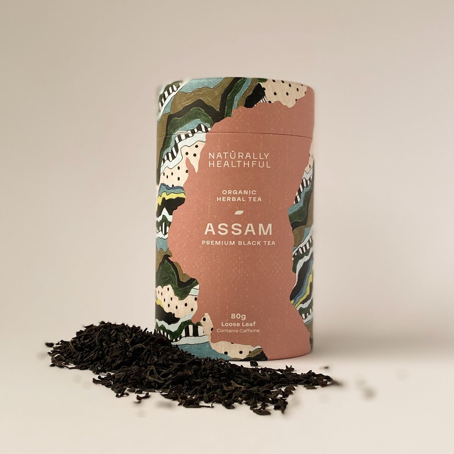 Assam tea cylinder with black loose leaf tea in front of it